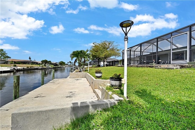 dock area with a water view, a yard, and glass enclosure