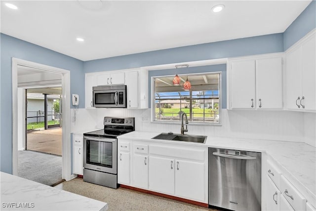 kitchen with stainless steel appliances, a sink, white cabinets, recessed lighting, and light stone counters