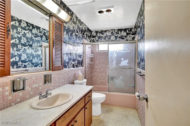 full bath featuring vanity, toilet, speckle patterned floor, and combined bath / shower with glass door