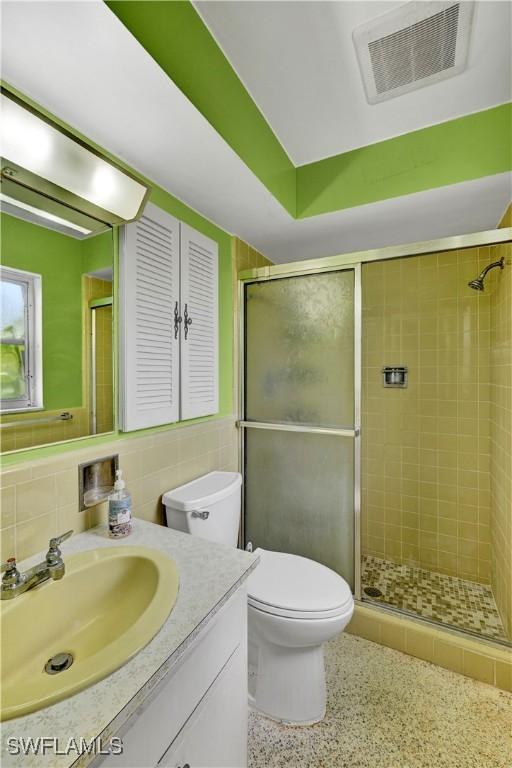 1414 Shelby Pkwy, Cape Coral, FL 33904 - full bathroom featuring vanity, a shower stall, toilet, speckled floor, and tile walls