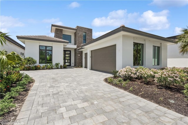 view of front facade featuring stucco siding, a garage, and decorative driveway