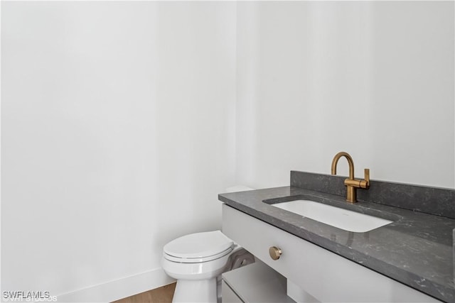 bathroom with vanity, toilet, and baseboards
