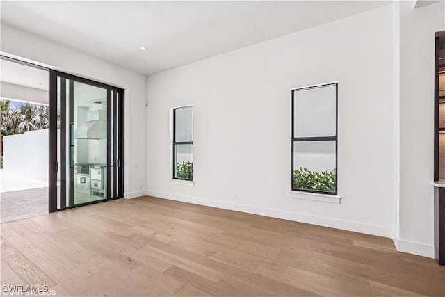 empty room with light wood finished floors, baseboards, and recessed lighting