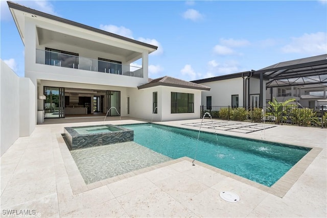 back of property with stucco siding, a patio area, a balcony, and a pool with connected hot tub