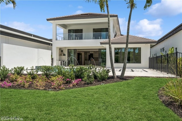 rear view of house featuring a balcony, stucco siding, and a patio