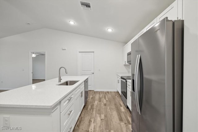 kitchen featuring appliances with stainless steel finishes, a sink, lofted ceiling, white cabinetry, and light wood finished floors