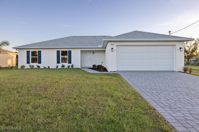 ranch-style home featuring stucco siding, decorative driveway, a front lawn, and a garage