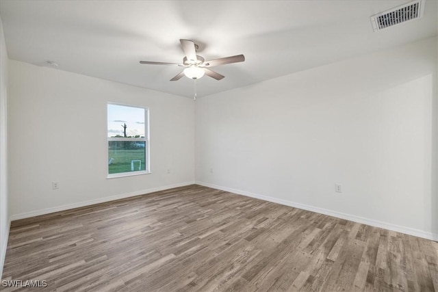 empty room with wood finished floors, ceiling fan, baseboards, and a smoke detector