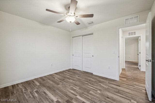 unfurnished bedroom with wood finished floors, a closet, baseboards, and ceiling fan