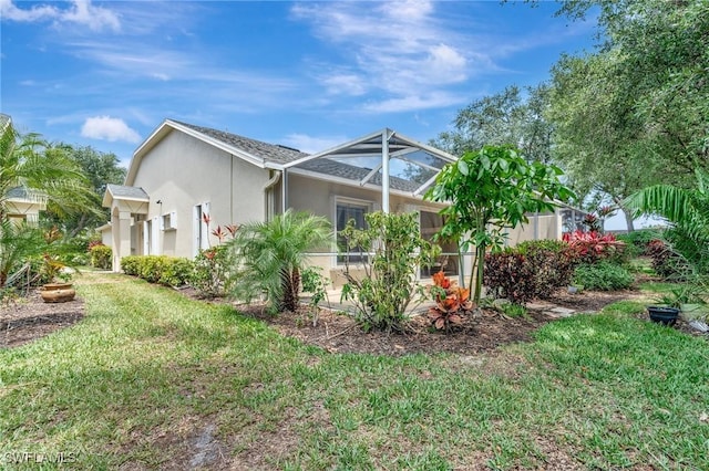 8012 Sivon Way Unit 902, Naples, FL 34119 - view of home's exterior featuring stucco siding, a yard, and glass enclosure