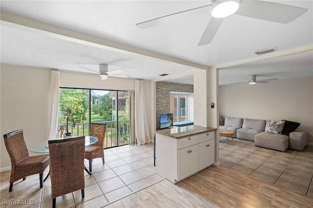 430 Meadowlark Ln Unit 430B, Naples, FL 34105 - kitchen featuring ceiling fan, open floor plan, white cabinets, stone counters, and light wood-style floors