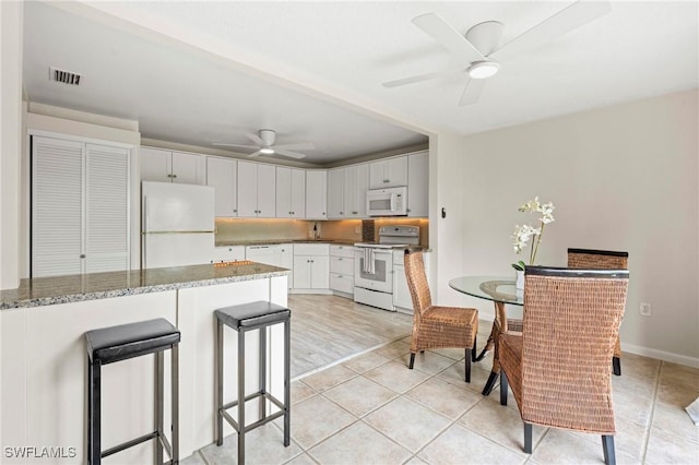 430 Meadowlark Ln Unit 430B, Naples, FL 34105 - kitchen with white appliances, a ceiling fan, white cabinets, light tile patterned flooring, and light stone countertops