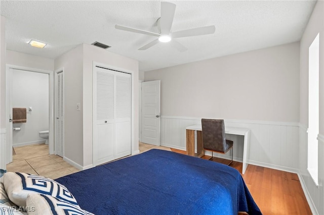 430 Meadowlark Ln Unit 430B, Naples, FL 34105 - bedroom featuring wainscoting, a textured ceiling, a ceiling fan, light wood-type flooring, and connected bathroom