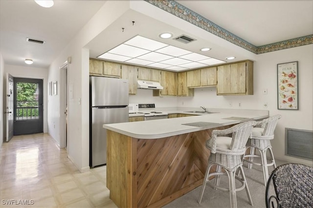 kitchen featuring freestanding refrigerator, under cabinet range hood, stove, a peninsula, and light countertops