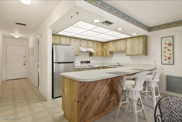kitchen with freestanding refrigerator, under cabinet range hood, stove, a peninsula, and light countertops