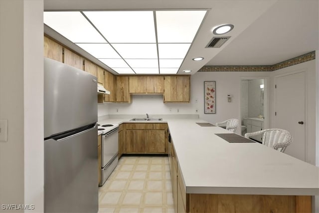 kitchen with freestanding refrigerator, white electric range oven, a peninsula, under cabinet range hood, and light countertops