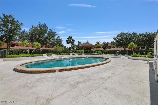 community pool with a patio area, a gazebo, and fence
