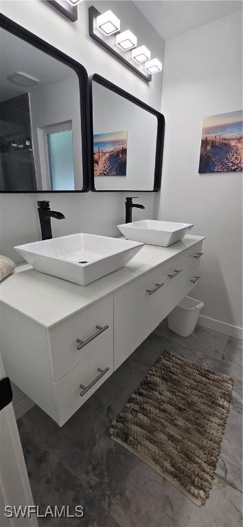 full bathroom with double vanity and baseboards