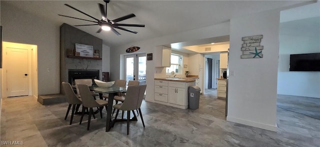 dining area featuring a fireplace, a ceiling fan, french doors, and high vaulted ceiling
