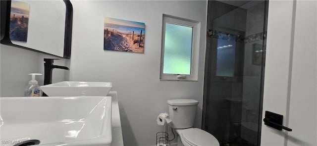 full bath featuring a sink, a shower stall, toilet, and baseboards