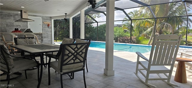 swimming pool featuring a patio, an outdoor kitchen, outdoor dining area, and glass enclosure