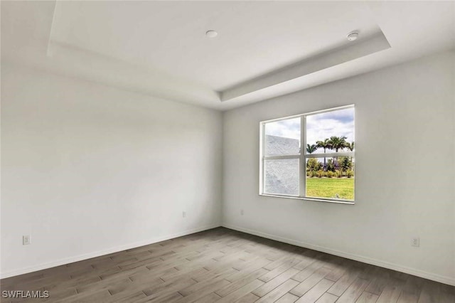 44311 Panther Dr, Punta Gorda, FL 33982 - empty room with a tray ceiling, wood finished floors, and baseboards