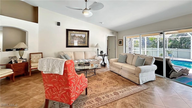 living room featuring lofted ceiling, a ceiling fan, tile patterned floors, and arched walkways