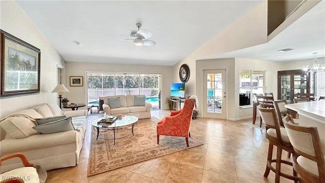 living room with ceiling fan, plenty of natural light, vaulted ceiling, and light tile patterned floors