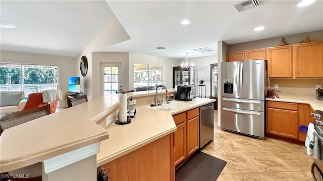 kitchen featuring stainless steel appliances, a sink, light countertops, healthy amount of natural light, and recessed lighting