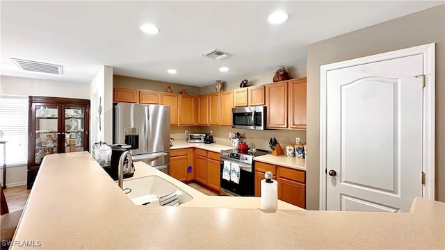 kitchen featuring appliances with stainless steel finishes, a sink, light countertops, and recessed lighting