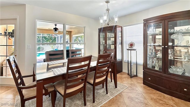 dining room featuring light tile patterned floors, a ceiling fan, a chandelier, and baseboards