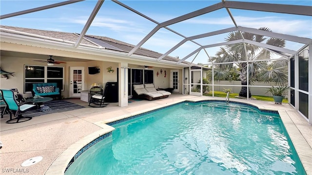 outdoor pool with a ceiling fan, a patio area, an outdoor hangout area, and glass enclosure