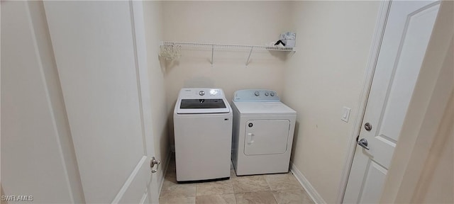 laundry room featuring washing machine and clothes dryer and baseboards