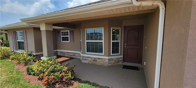 view of exterior entry featuring stone siding and stucco siding