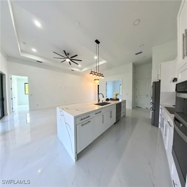 kitchen featuring black appliances, a sink, a tray ceiling, open floor plan, and white cabinetry