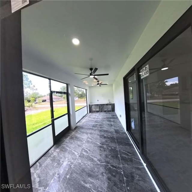 unfurnished sunroom featuring a ceiling fan