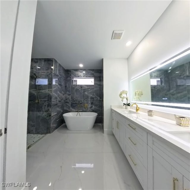 full bath with marble tiled floors, a marble finish shower, a freestanding tub, double vanity, and recessed lighting