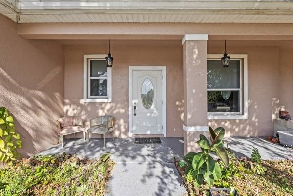 857 Bedford Dr, Lehigh Acres, FL 33974 - entrance to property featuring a porch and stucco siding