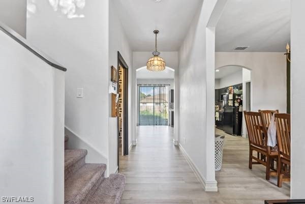857 Bedford Dr, Lehigh Acres, FL 33974 - foyer with arched walkways, light wood-type flooring, stairs, and baseboards