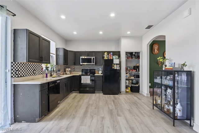 857 Bedford Dr, Lehigh Acres, FL 33974 - kitchen featuring black appliances, arched walkways, light countertops, tasteful backsplash, and light wood finished floors