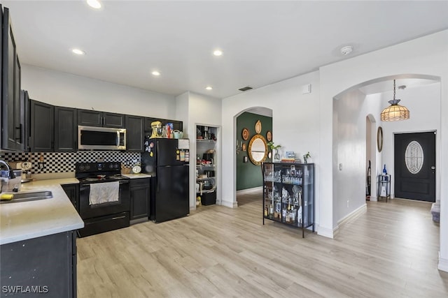 857 Bedford Dr, Lehigh Acres, FL 33974 - kitchen with black appliances, arched walkways, a sink, tasteful backsplash, and light wood-type flooring