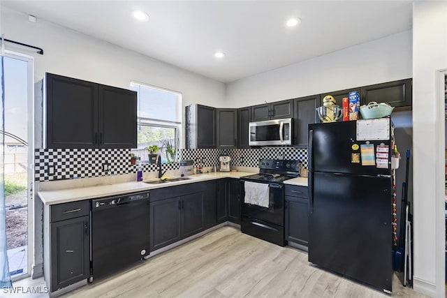 857 Bedford Dr, Lehigh Acres, FL 33974 - kitchen with black appliances, a sink, light countertops, decorative backsplash, and light wood-style flooring