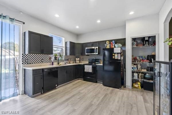 857 Bedford Dr, Lehigh Acres, FL 33974 - kitchen with black appliances, tasteful backsplash, light wood finished floors, light countertops, and recessed lighting