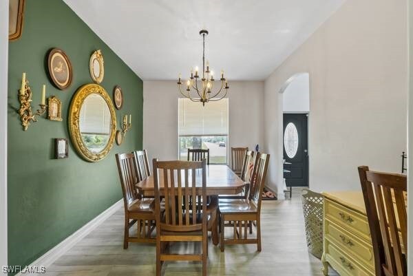 857 Bedford Dr, Lehigh Acres, FL 33974 - dining area with arched walkways, a chandelier, wood finished floors, and baseboards
