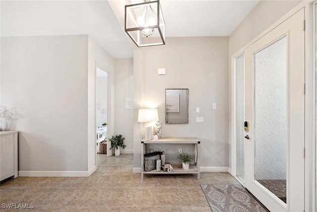 tiled foyer with a chandelier and baseboards