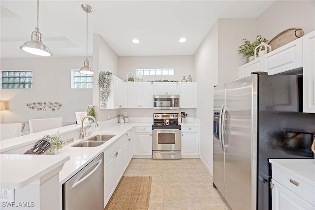 kitchen with stainless steel appliances, a sink, light countertops, a peninsula, and white cabinetry