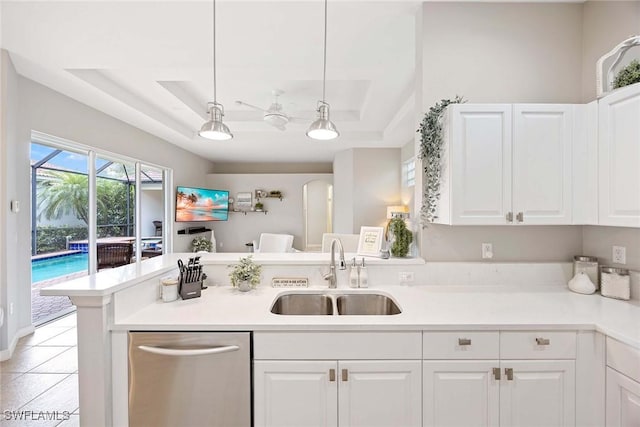 kitchen with a sink, a raised ceiling, stainless steel dishwasher, and white cabinets