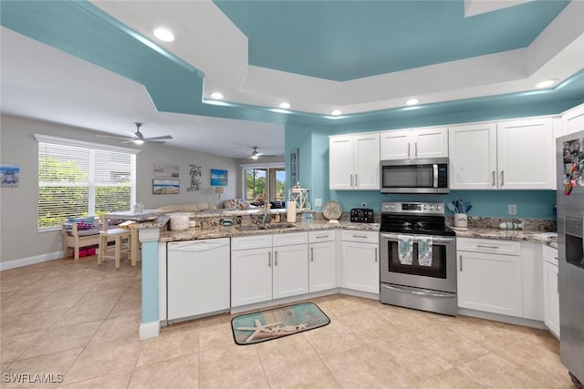 10115 Colonial Country Club Blvd Unit 2110, Fort Myers, FL 33913 - kitchen featuring stainless steel appliances, a sink, a peninsula, a tray ceiling, and white cabinetry