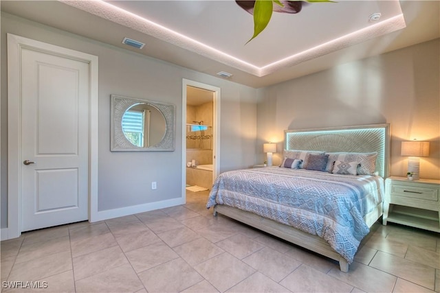 bedroom with a tray ceiling, baseboards, connected bathroom, and light tile patterned flooring