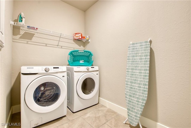 clothes washing area with washer and clothes dryer, baseboards, and light tile patterned flooring